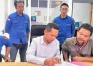 Mawardi Khairi (baju putih), salah satu dari tiga tersangka, menandatangani berkas. (Dok. Radarlombok.co.id)