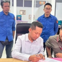 Mawardi Khairi (baju putih), salah satu dari tiga tersangka, menandatangani berkas. (Dok. Radarlombok.co.id)